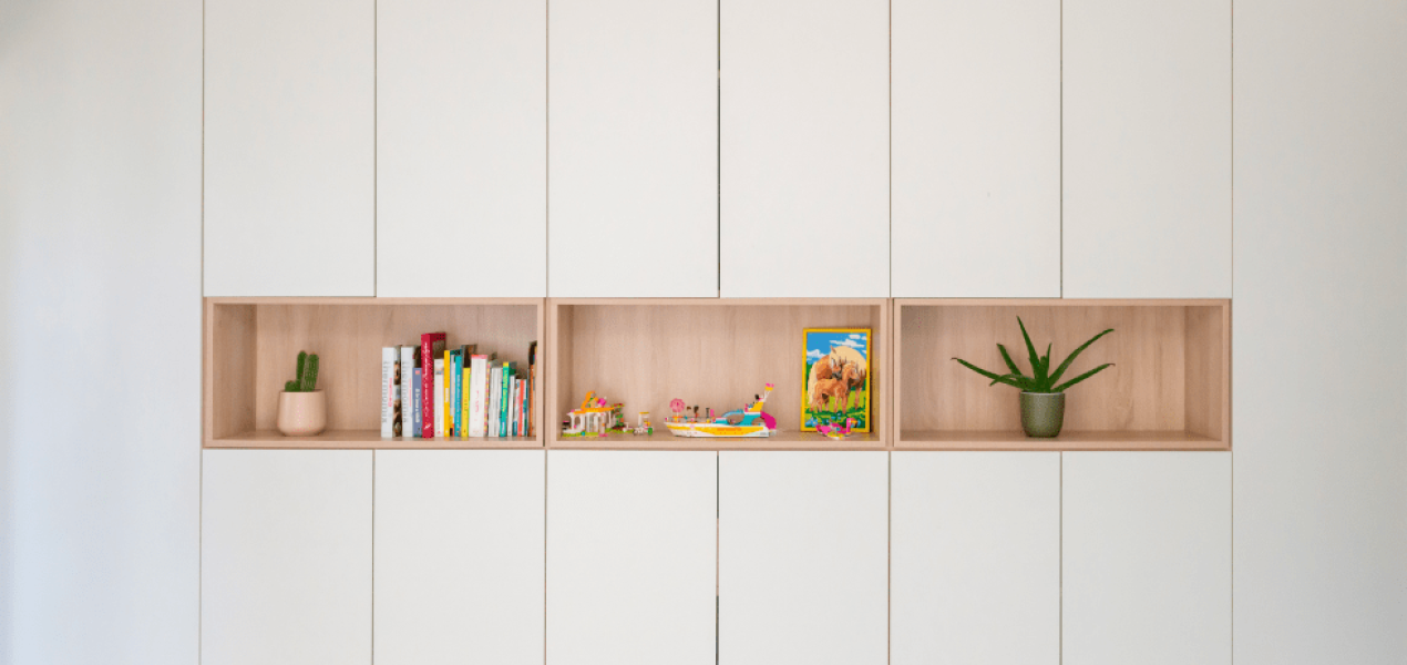 Bibliothèque minimaliste blanche avec sections ouvertes en bois, combinant rangement et exposition pour un design intérieur chic et fonctionnel.